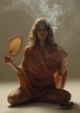 A scarf when it's cooler. Sitting cross-legged in a studio with the tan Sand Om Sarong wrapped around her shoulders, incense smoke rising, fan in hand.