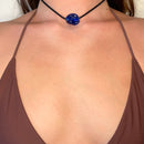 Beach jewellery that suits a sarong. Worn as a choker, the cobalt blue glass pendant at the throat above a brown bikini top.